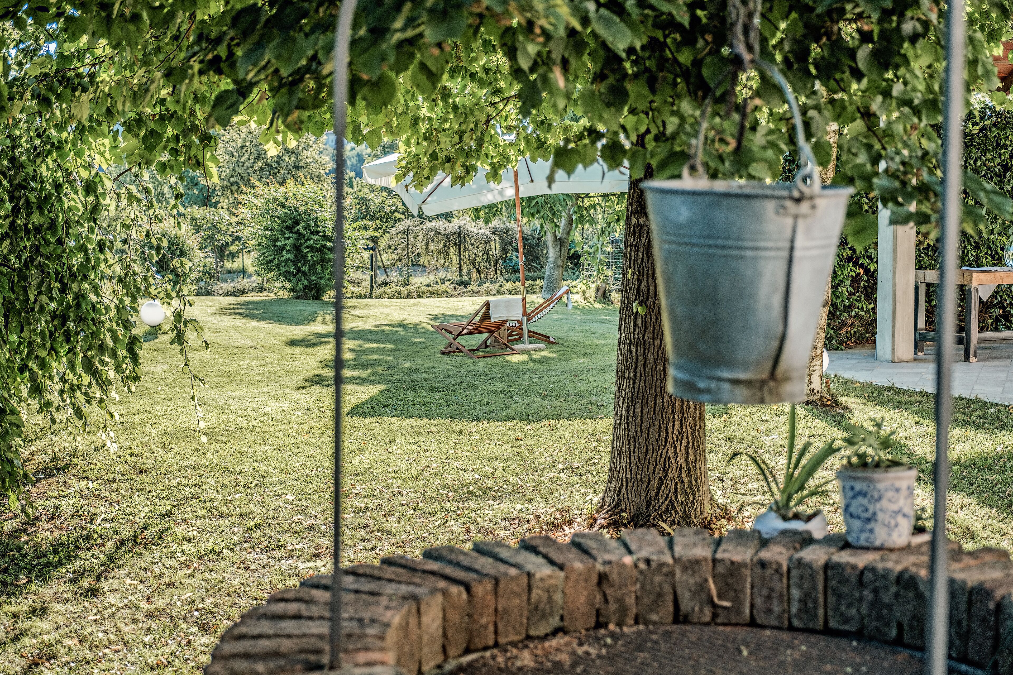 Un jardín con una hamaca, un balde colgante y una planta en maceta.