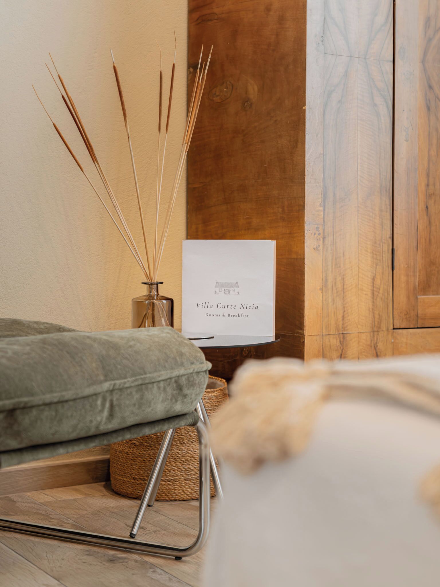 A room with a bed, a bedside table with a glass vase, and a sign indicating Villa Curte Nicia Rooms & Breakfast.