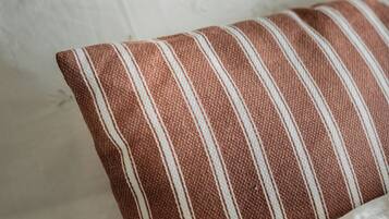 A close-up of a bed with white bedding and a striped pillow.