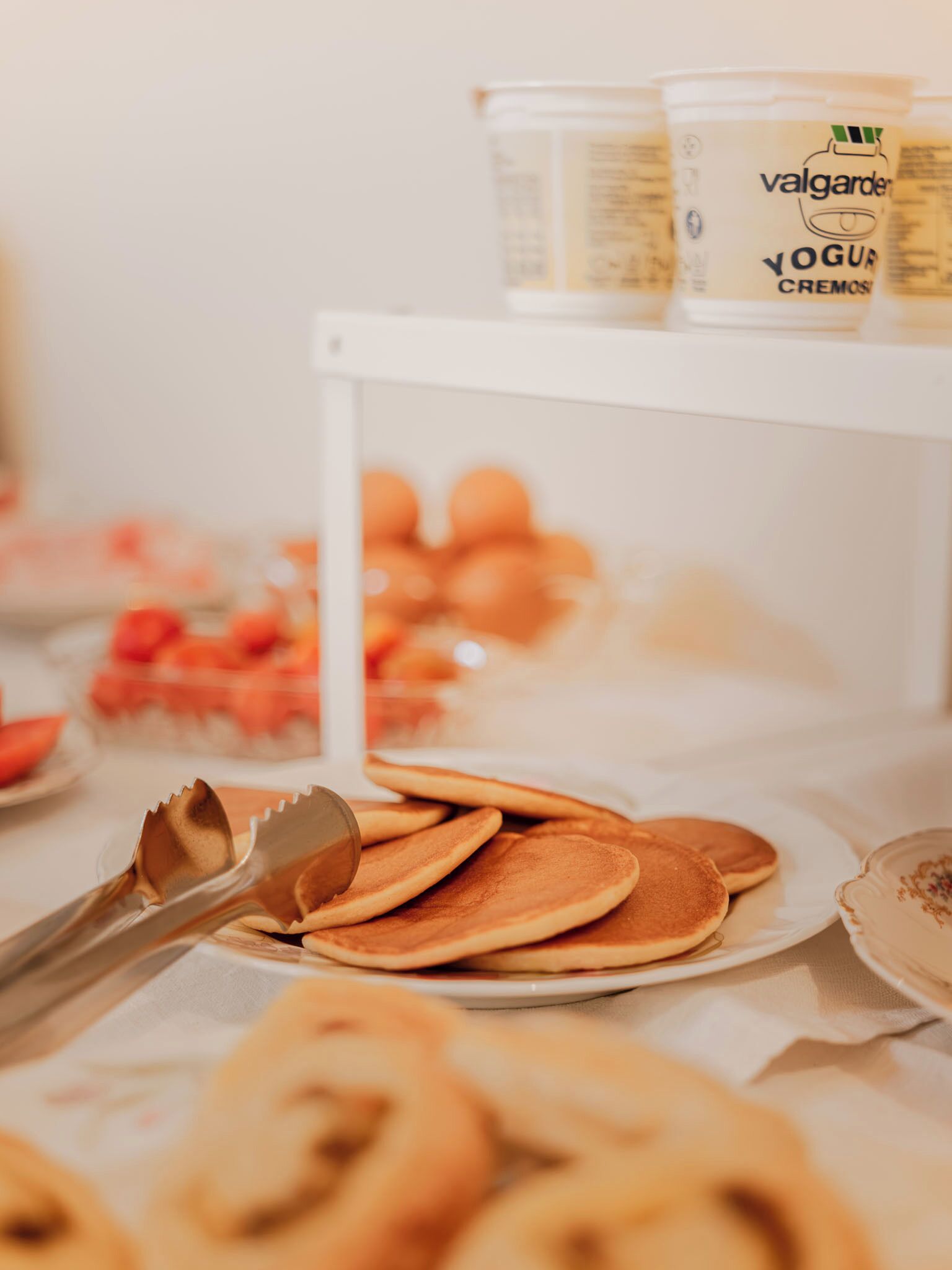 Ein Buffet mit Pfannkuchen, einem Joghurtbecher und einer Obstschale.
