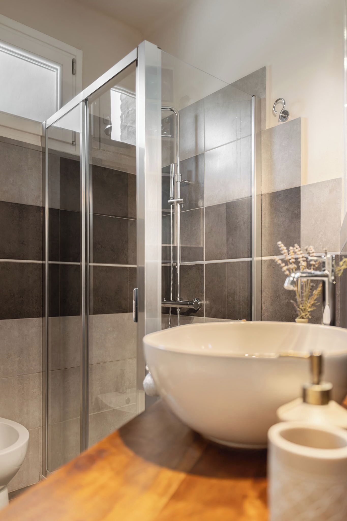 A modern bathroom with a glass shower enclosure, a large vessel sink, and a toilet.