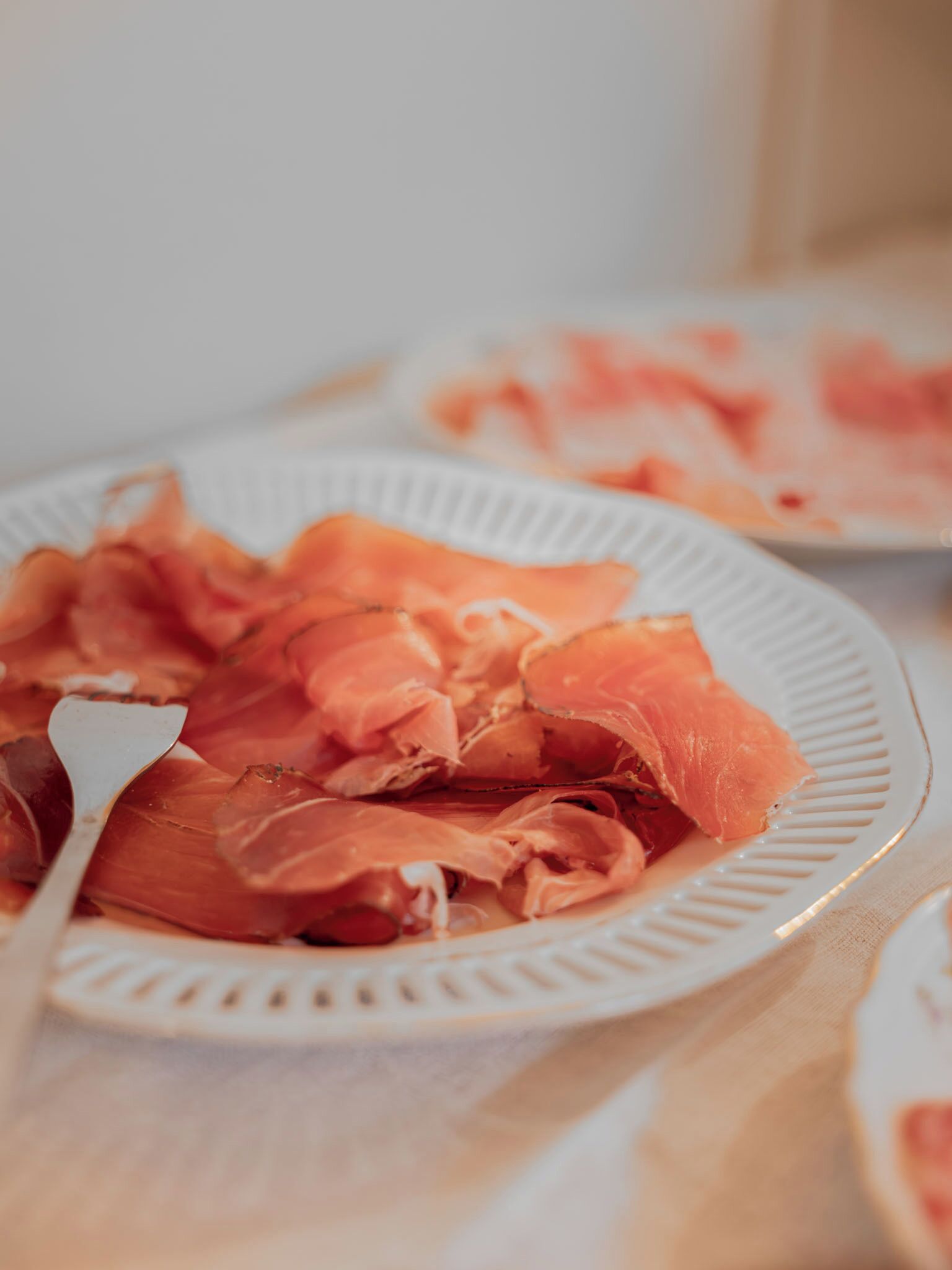 A plate of sliced cured meat on a white plate.