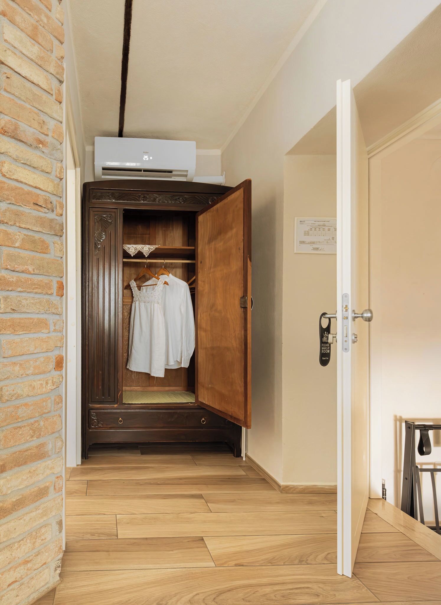 Une pièce avec une armoire en bois, un vêtement blanc suspendu et une porte sur laquelle est apposée une pancarte.