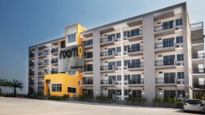 A multi-story hotel with a prominent 'room9' sign, balconies, and a parking area. - Room 9 Residence - Adult Only (Pluak Daeng)