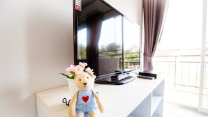 A plush toy with a heart on its chest sitting on a white surface next to a television. - Room 9 Residence - Adult Only (Pluak Daeng)