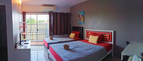 A hotel room with two beds, a desk, a chair, a table, and a window with curtains.