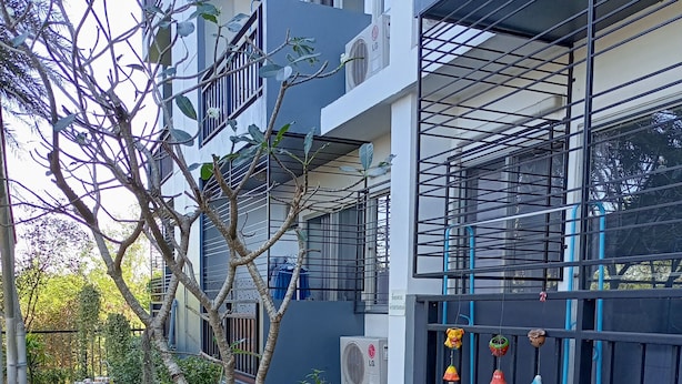A courtyard with potted plants, a blue hose, and an air conditioning unit. - Room 9 Residence - Adult Only (Pluak Daeng)