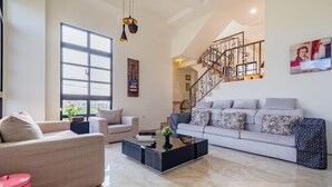 Un amplio salón con un ventanal grande, una escalera y una mesa de centro moderna.