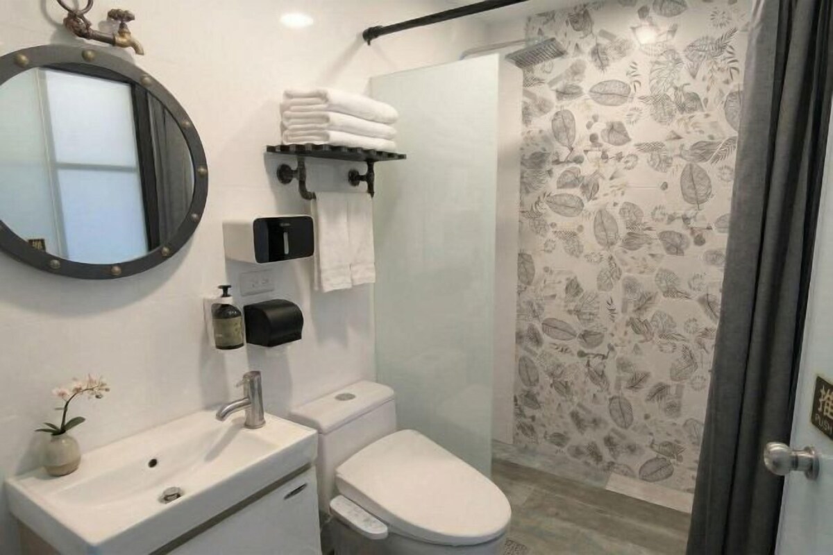 Un baño con inodoro, lavamanos, espejo, toallero y cortina de ducha.