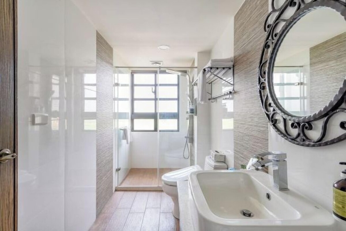 A modern bathroom with a glass shower enclosure, a large mirror, and a white sink.