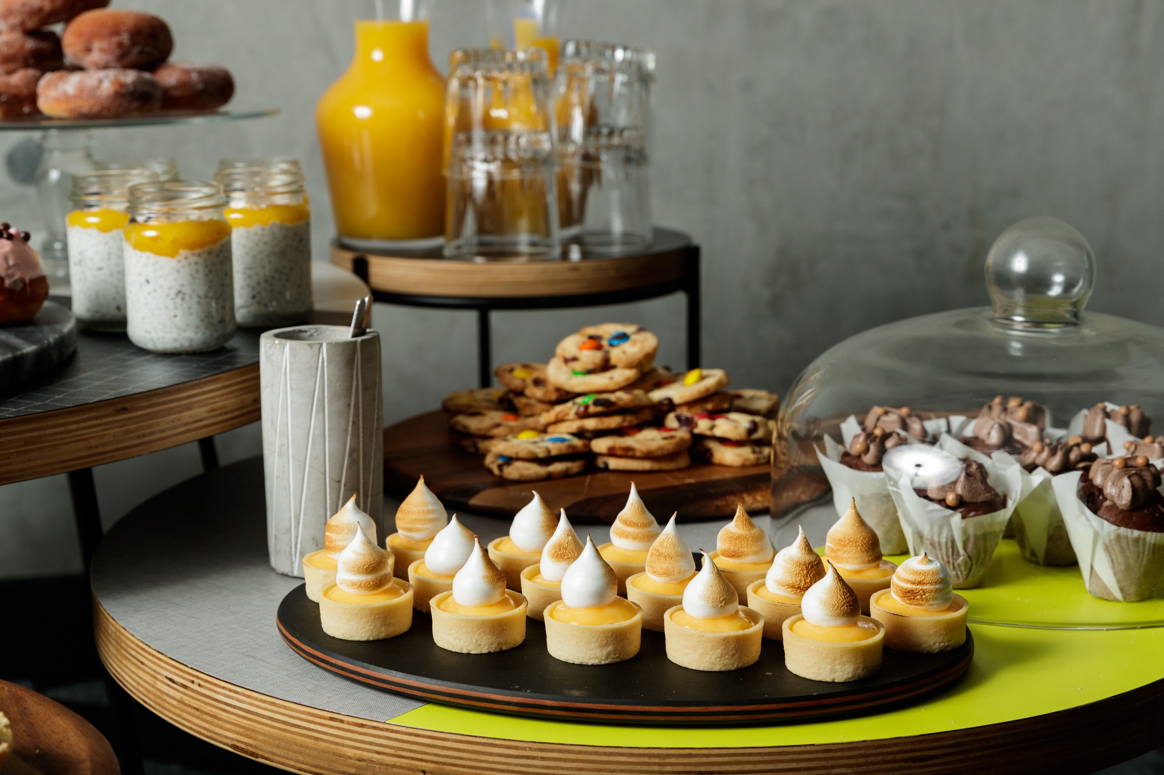 A buffet with various desserts, including mini cakes and cookies, arranged on a wooden table.