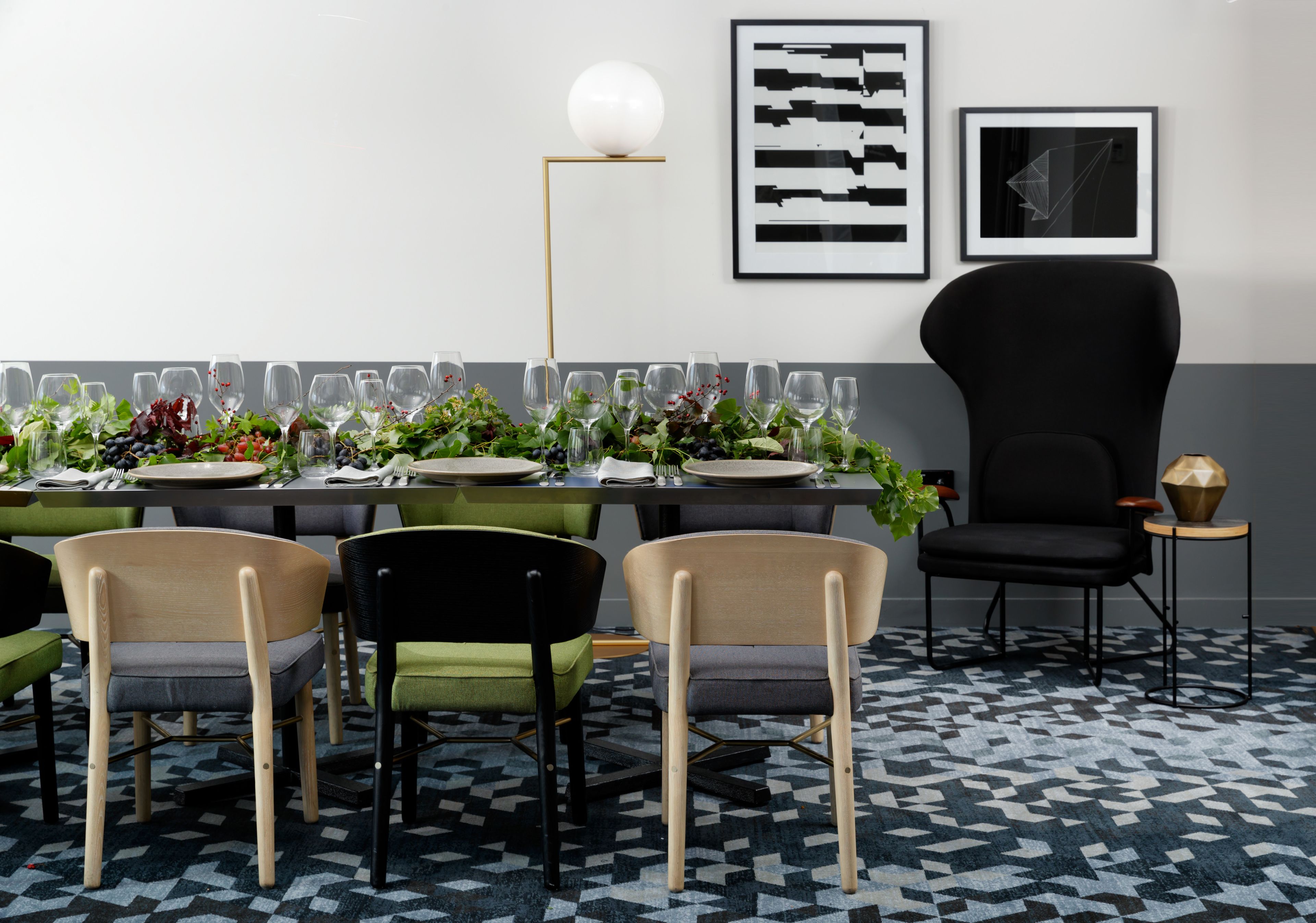 A dining area with a table set for a meal, surrounded by chairs, a floor lamp, and framed artwork on the wall.