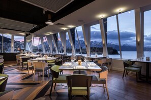 A restaurant with tables set for dining, large windows offering mountain views, and a modern interior design. - QT Queenstown (Queenstown)
