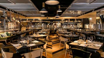 A restaurant with multiple dining tables, chairs, and hanging pendant lights.