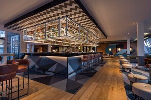 A modern bar area with a central bar counter, multiple seating options, and a unique ceiling design.