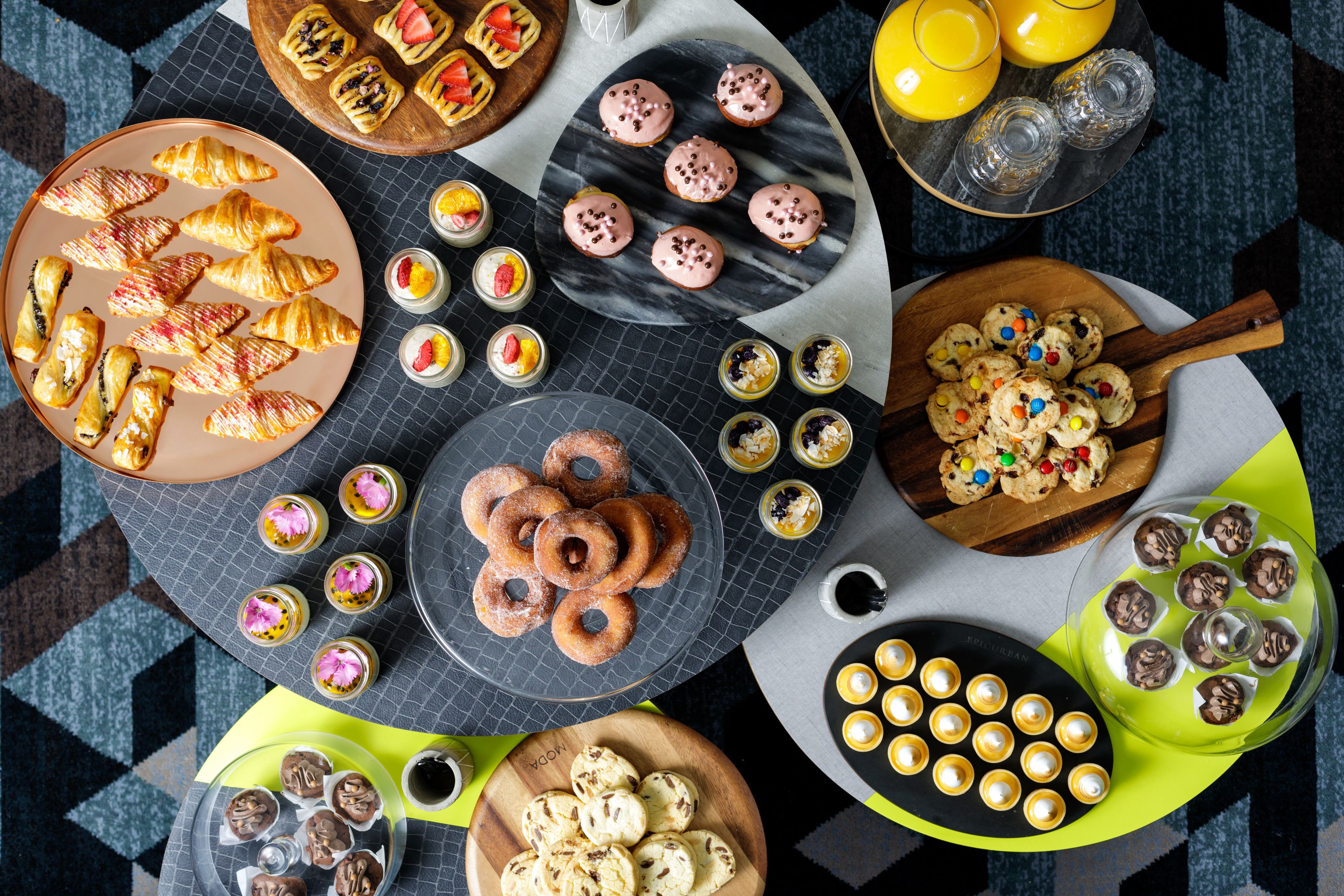 Ett stort urval av bakverk och desserter, presenterade på olika fat och brickor.