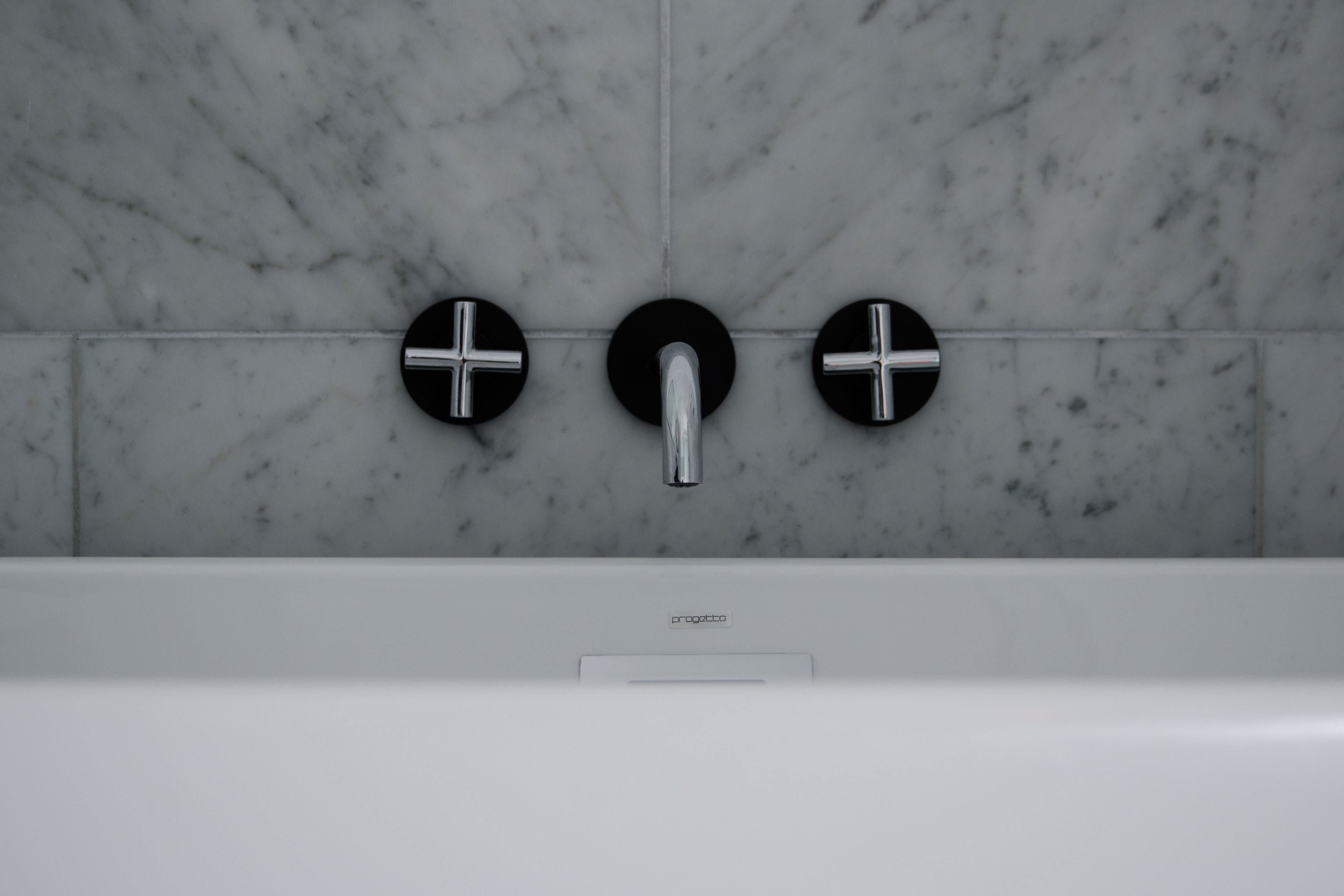 Un baño con un grifo moderno y tres pomos redondos, negros.