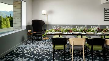 A dining area with a table set for a meal, chairs, a lamp, and a view of mountains through a window.