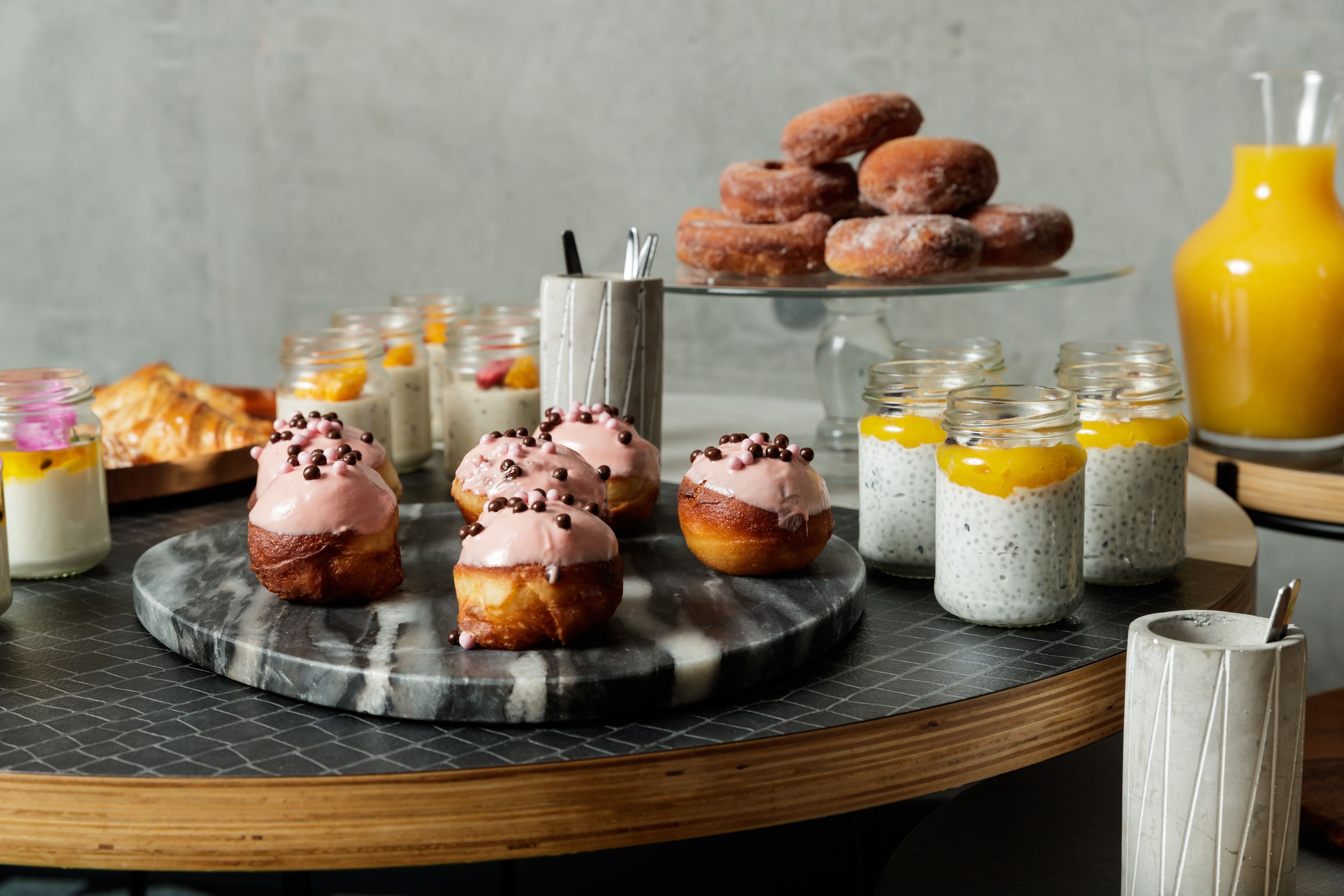 A breakfast buffet with pastries, muffins, and a variety of beverages.