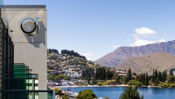A modern building with a circular window and a view of a lake and mountains. - QT Queenstown (Queenstown)
