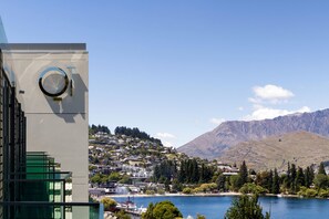 A modern building with a circular window and a view of a lake and mountains. - QT Queenstown (Queenstown)