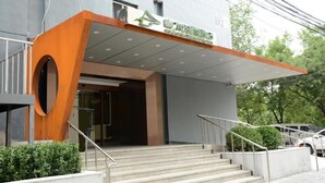 A hotel entrance with a modern design, featuring a prominent wooden structure and a covered entrance area.