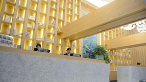 A reception area with a marble counter, wooden shelving with books, and a large window with a view of the sky.