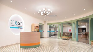 A reception area with a modern design, a large logo on the wall, and a patterned floor. - Nest by TreeHouse Bhiwadi (Tijara)