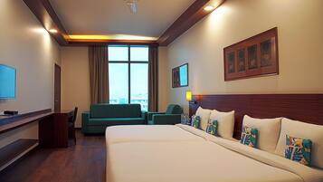 Une chambre d’hôtel avec un grand lit, un bureau, un canapé vert et un téléviseur.