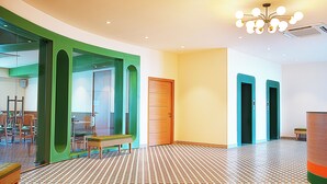 A spacious hallway with a patterned floor, a green accent wall, and a wooden door. - Nest by TreeHouse Bhiwadi (Tijara)