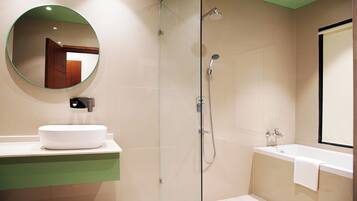 A modern bathroom with a round mirror, a white sink, a glass-enclosed shower, and a bathtub.