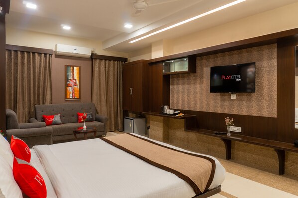 Une chambre d’hôtel équipée d’un lit, d’un canapé, d’une télévision et d’un mini-bar.