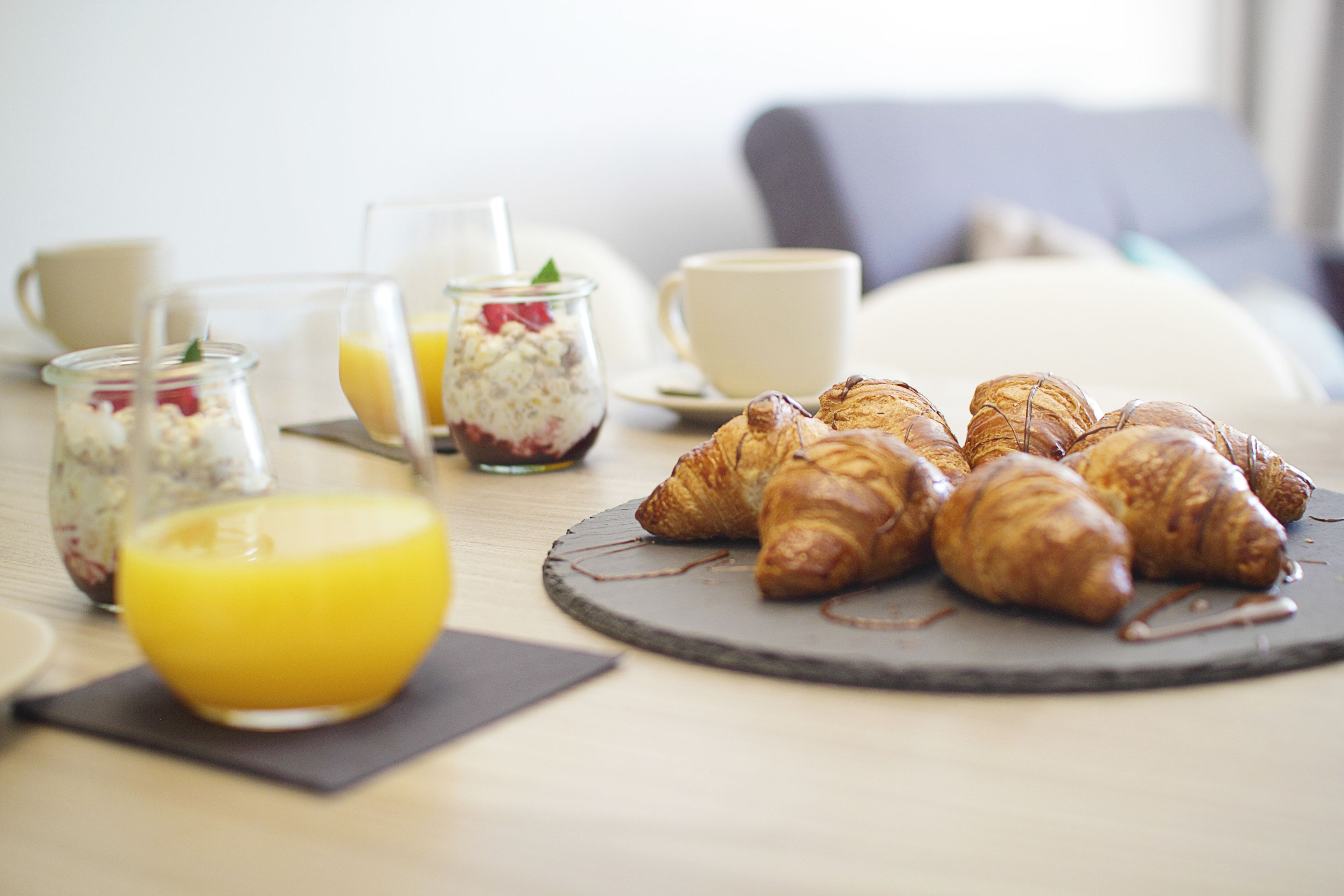 Una mesa con croissants, un vaso de zumo de naranja y otro vaso de zumo de naranja.