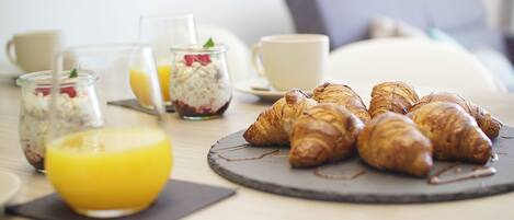 Una mesa con croissants, un vaso de zumo de naranja y otro vaso de zumo de naranja.