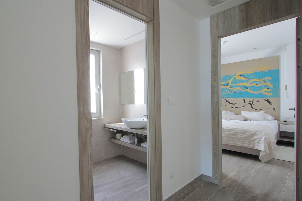 A modern bathroom with a large mirror, a sink, and a toilet.