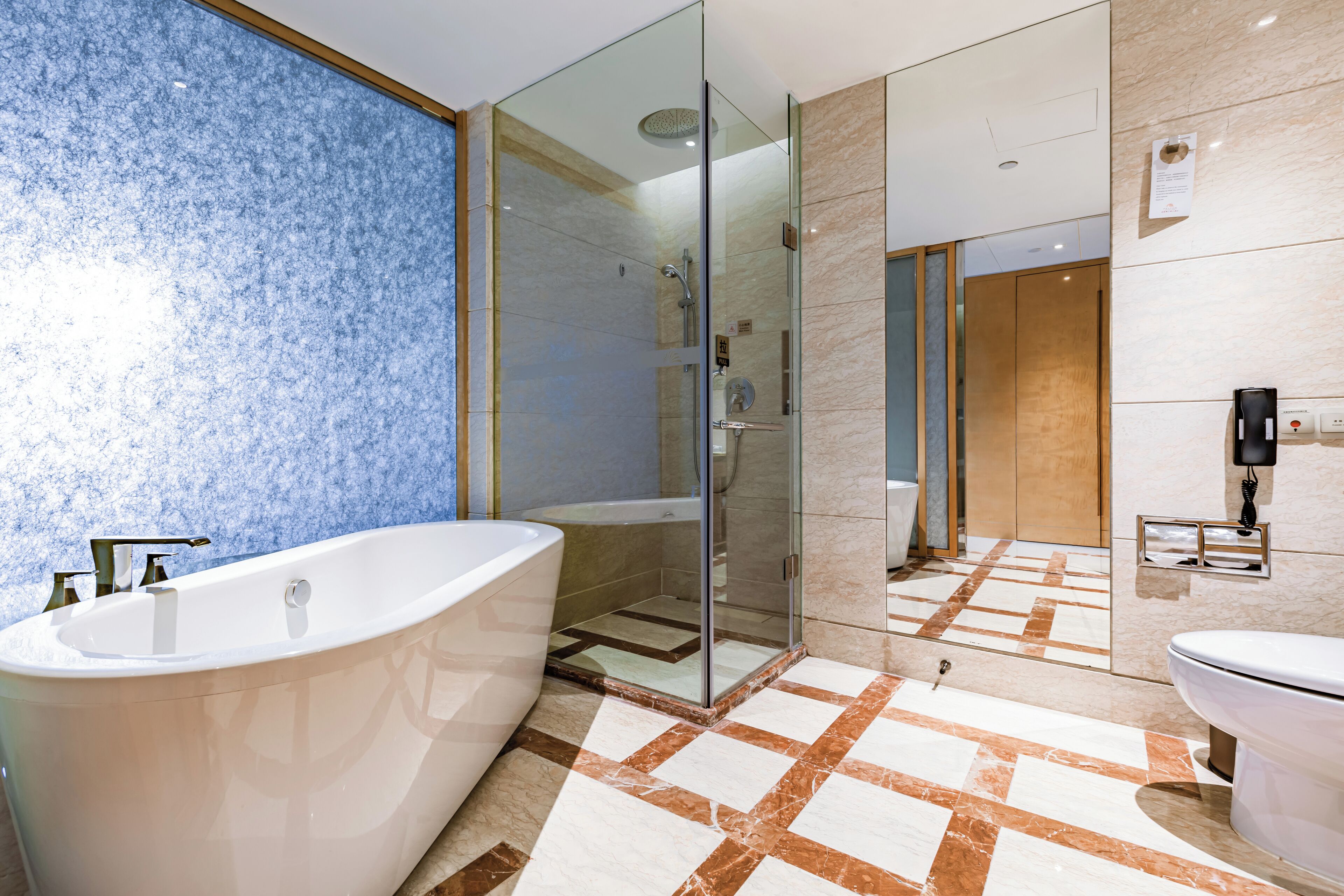 Een moderne badkamer met een vrijstaand bad, een douche met glazen wand en een toilet.