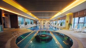 An indoor swimming pool with a central fountain, surrounded by lounge chairs and potted plants. - Felton Grand Hotel Chengdu (Chengdu)