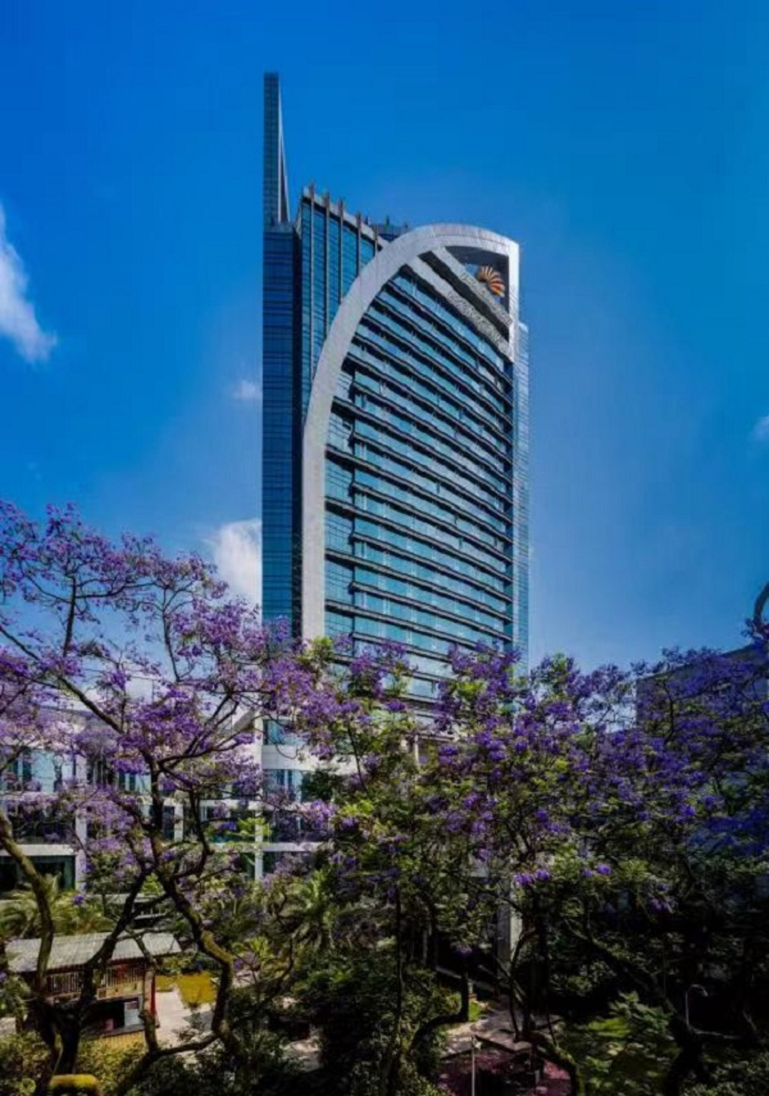 Un moderno edificio de gran altura con fachada curva y un logotipo destacado en la parte superior.