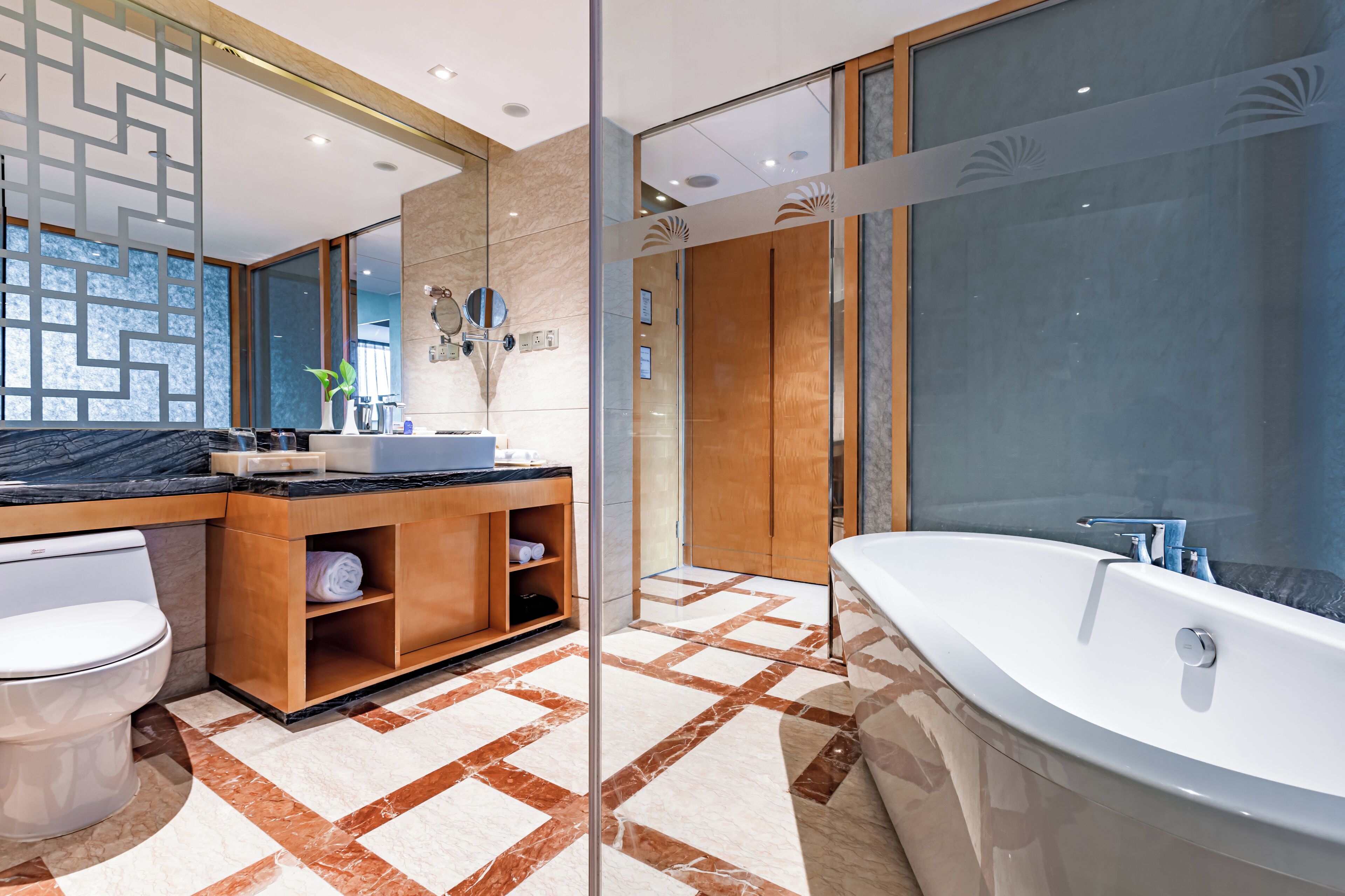 A modern bathroom with a large bathtub, a separate sink area, and a toilet.