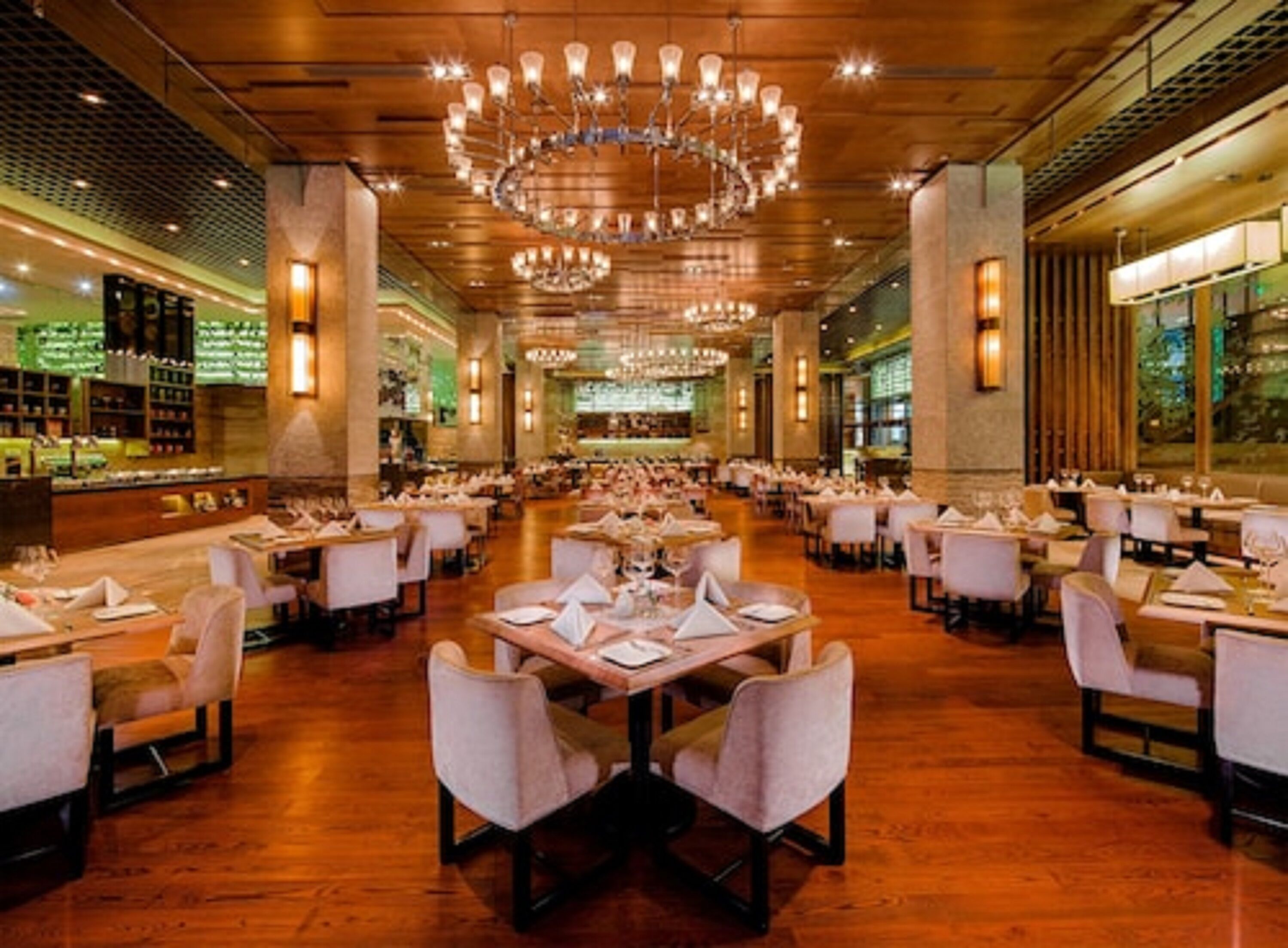 Ein geräumiges Restaurant mit mehreren Tischen und Stühlen, warmer Beleuchtung und einem modernen Kronleuchter.
