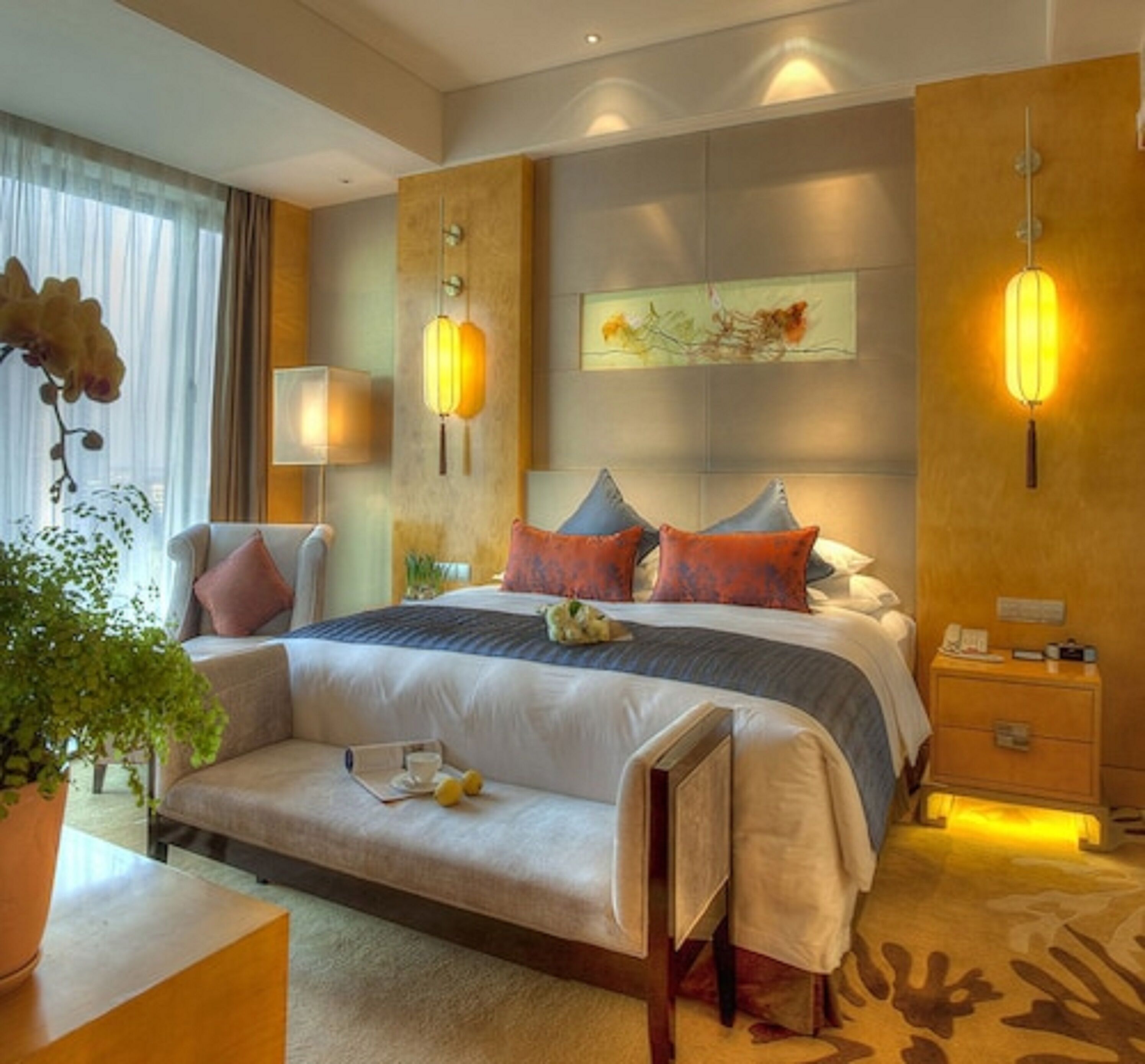 A modern hotel room with a large bed, bedside tables, a desk, and a chair.