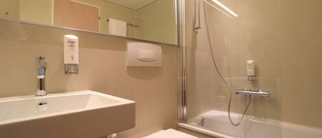 A modern bathroom with a glass-enclosed shower, a white sink, and a toilet.