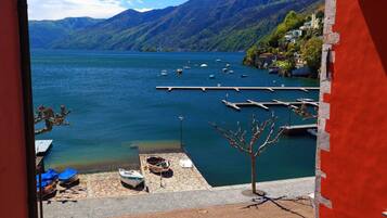 A view of a lake with boats docked at a pier, surrounded by mountains and buildings.