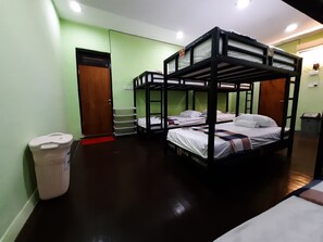 Een kamer met stapelbedden, een prullenbak, een deur en een plank met spullen.