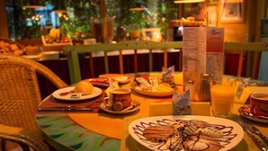 A restaurant setting with a table set for a meal, including plates of food, a menu, and a drink. - Hotel California (Zürich)