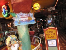 A carousel with a sign reading "Welcome to PJ Island" and a "Please Wait to Be Seated" sign.