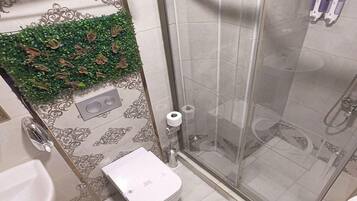 Une salle de bain avec une douche à parois en verre, des toilettes et un lavabo.