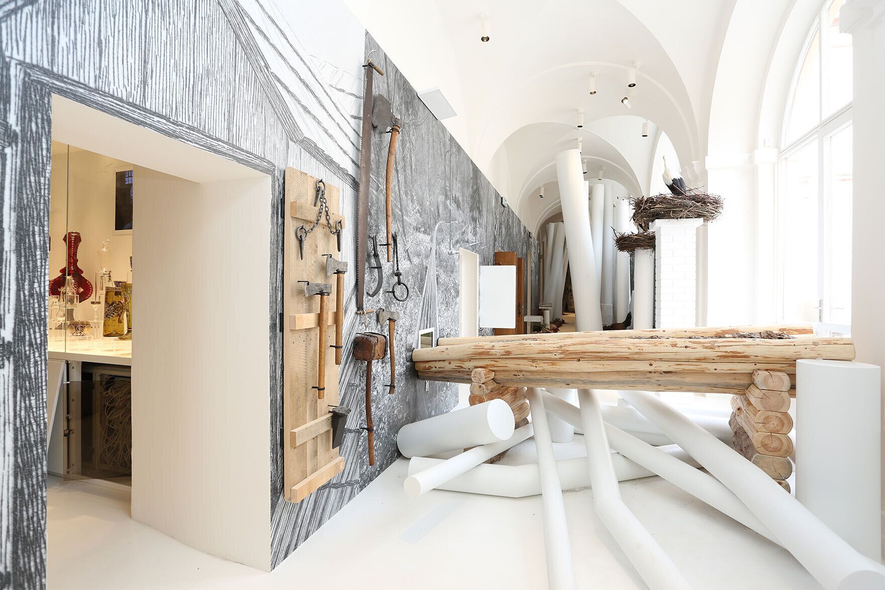 Un interior moderno con un largo pasillo, una mesa de madera y diversas herramientas en la pared.
