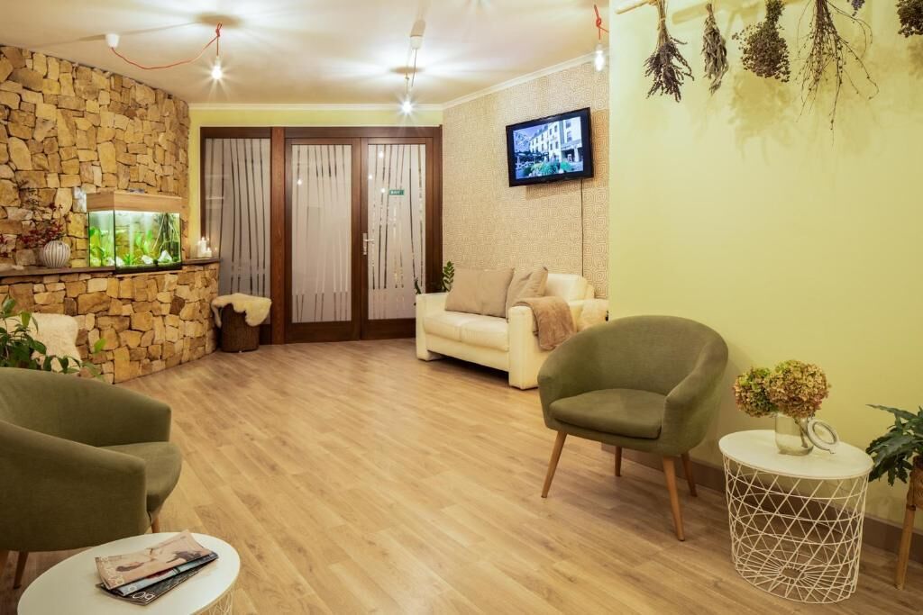 A living room with a stone wall, a sofa, a green armchair, a round side table, and a television mounted on the wall.