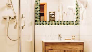 A bathroom with a glass-enclosed shower, a wooden vanity with a mirror, and a tiled backsplash.